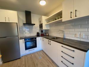 uma cozinha com armários brancos e um frigorífico de aço inoxidável em Luckie Lane Homestay em Queenstown