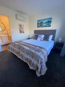 a bedroom with a large bed with a blanket on it at Luckie Lane Homestay in Queenstown