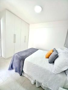a white bedroom with a bed with pillows on it at Apt em condomínio de luxo à beira mar de Jatiúca in Maceió