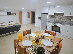 una cocina con una mesa con platos y vasos de zumo de naranja en Apartamentos Playa Area Grande, en San Vicente de O Grove
