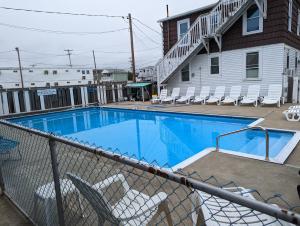 a swimming pool with chairs in front of a building at 7 Beachside inn in Hampton