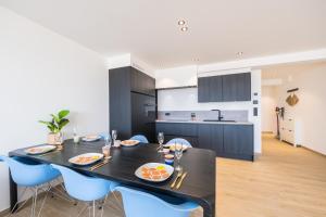 a kitchen and dining room with a black table and blue chairs at Apartment 2 bedrooms with magnificent seaview and free parking in Ostend