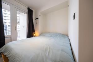 a white bedroom with a bed and a window at Apartment 2 bedrooms with magnificent seaview and free parking in Ostend