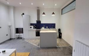 a kitchen with white counters and a blue tile wall at Doncaster City Centre Deluxe Whole Apartment sleeps 4 D2 in Doncaster +14 photos