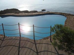 a swimming pool next to the ocean with a fence at Cap sa Sal Lofts in Begur