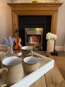 a table with three tea pots and a fireplace at The Ramblers Rest - whole apartment - pet friendly - close to amenities and walks in Edzell