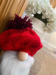 Czerwono-biały kapelusz siedzący obok wazy kwiatów w obiekcie The Ramblers Rest - whole apartment - pet friendly - close to amenities and walks w mieście Edzell