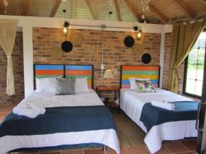 2 camas en una habitación con una pared de ladrillo en Posada Rural, Colinas y Senderos, en Paipa