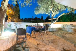 un patio con mesa y sillas bajo un árbol en Amazing house W pool and big sunny terrace close to sea & beach en Splitska