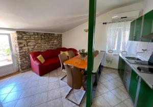 a kitchen and a living room with a table and a red couch at Apartment Moris in Vodnjan