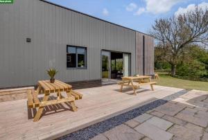 un patio con 2 mesas de picnic y un edificio en Fen Lane Lodge, en Snetterton