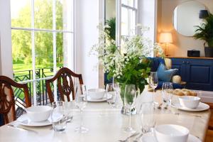 una mesa con vasos y un jarrón de flores. en A Rare Georgian Crescent Residence with parking en Bath