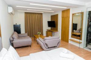 uma sala de estar com duas cadeiras e uma televisão em Hotel Pazari & Apartments em Korçë
