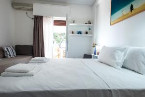 a bedroom with a large white bed and a window at Melina Beachfront Apartment in Malaki