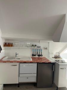 - une cuisine blanche avec évier et cuisinière dans l'établissement Les Gîtes de La Maison Bleue d'Estialescq, à Estialescq