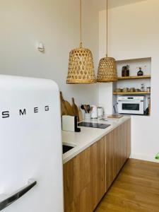 a kitchen with white counters and wooden cabinets and pendant lights at Appartement Casadilonda - Casadibastia - Vue mer Citadelle in Bastia