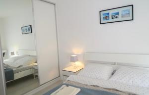 a white bedroom with a mirror and a bed at Biały apartament in Kołobrzeg