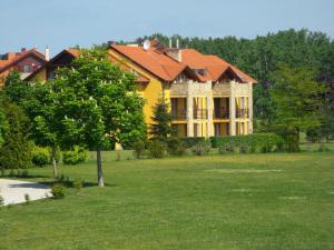 a large yellow house with an orange roof at Birdland Panorama Apartman in Bük