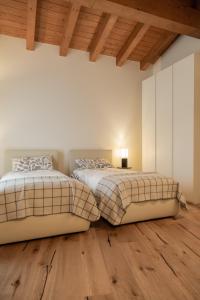2 camas en una habitación con suelo de madera en B&B Casa Pralunghi en Calvene