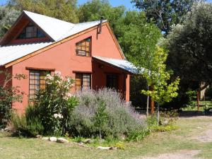 an orange house with a garden in front of it at CABAÑAS DE LA QUEBRADA in San Marcos Sierras