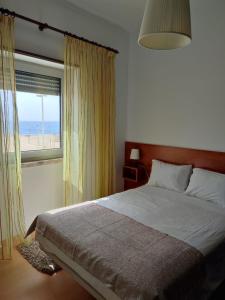 ナザレにあるApartamentos Carbel Marのベッドルーム1室(ベッド1台付)、ビーチを望む窓が備わります。