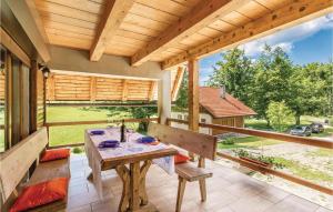 um alpendre com uma mesa de madeira e bancos em Cozy Home In Delnice With Kitchen em Delnice