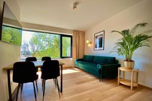 uma sala de estar com um sofá verde e uma mesa e cadeiras em SIRENA em Palanga