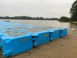 uma jangada azul sentada na costa de uma massa de água em Leśny Zakątek em Dźwierszno Małe