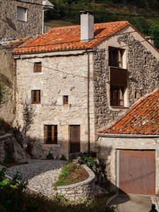 una antigua casa de piedra con techo naranja en Casa Rural La Ardina, en Sotres