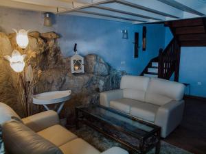sala de estar con sofá y pared de roca en Casa Rural La Ardina, en Sotres