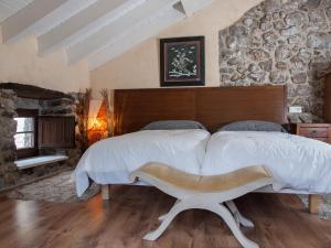 1 dormitorio con 1 cama grande y pared de piedra en Casa Rural La Ardina, en Sotres