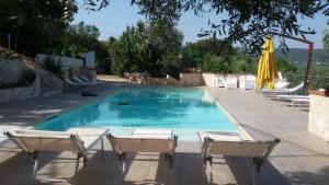 - une piscine avec 2 chaises et un parasol dans l'établissement Villa di Pasquale, à Peschici