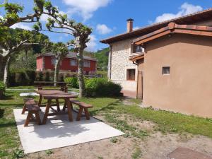 una mesa de picnic y bancos junto a un edificio en El Puentín del Sella con WiFi y parking gratuito, en Cangas de Onís