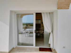 una puerta corredera de cristal que conduce a un patio con mesa en Perla delle Maldive en Marina di Pescoluse