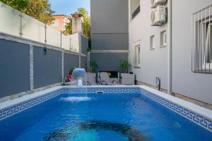 a swimming pool with a water fountain on a building at Apartments Hudovernik in Baška Voda