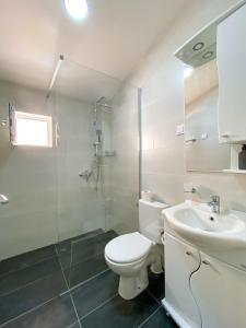 a white bathroom with a toilet and a sink at Apartments Monika in Budva