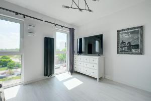 a white room with a tv and a dresser and windows at Targowa 10 London Studio in Warsaw