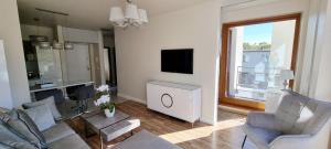 a living room with a couch and chairs and a tv at Apartament Perła Juraty in Jurata