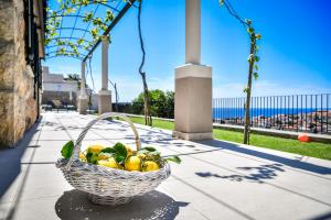 a basket of lemons sitting on a sidewalk with the ocean at Villa Oranž in Dubrovnik