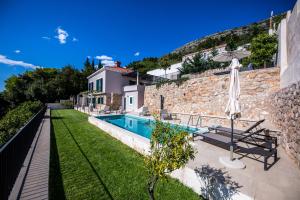 a house with a swimming pool next to a stone wall at Villa Oranž in Dubrovnik