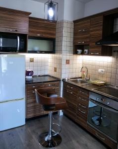 a kitchen with wooden cabinets and a bar stool in it at Nidius Apartment in Debrecen