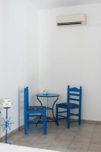 two blue chairs and a table with a air conditioner at Pigi Rooms in Apollonia