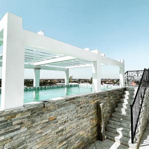 una piscina con pérgola blanca y escaleras en KAPINGA'S HOUSE en Saly Portudal