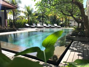 - une piscine avec des chaises longues à côté d'un complexe dans l'établissement Akatara Hotel, à Nusa Penida