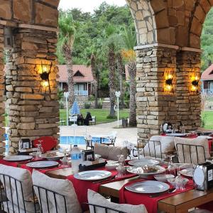 comedor con mesas y sillas y pared de piedra en Club Sun Village Hotel, en Adrasan