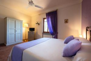 a bedroom with a large white bed with purple curtains at Tenuta Risalpiano in Pelago