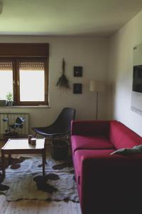 ein Wohnzimmer mit einem rosa Sofa und einem Tisch in der Unterkunft Kmetija Pečnik in Prevalje