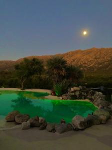 a pool of green water with the moon in the background at Fragancias Serranas in Cortaderas