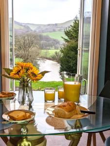 a glass table with two plates of food and orange juice at Aberhiriaeth Hall - Country House By River Dyfi in Cemmaes