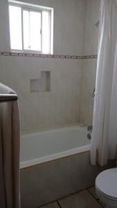 a bathroom with a tub and a toilet and a window at Confort Ejecutivo Suites Lindavista in Monterrey